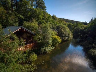 A view of a cabin by the millpond at Deerpark, Cornwall, Forest Holidays