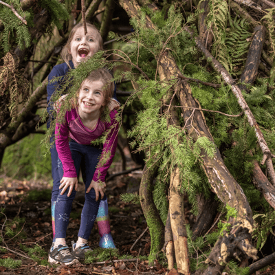 Two sisters playing in a forest den