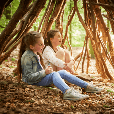 Two kids den building in the forest