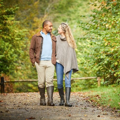 A couple walking together through a forest on their walking holiday 