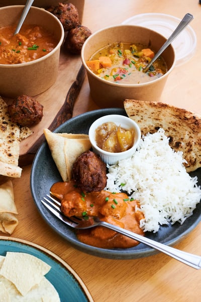 Plate full of curry, rice, naan and sides