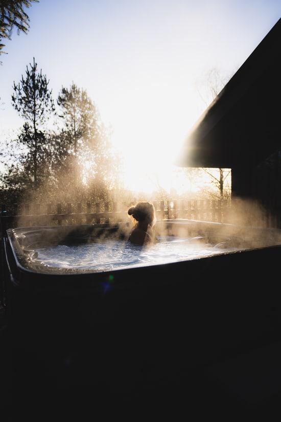 Person sat in a hot tub in morning sunrise