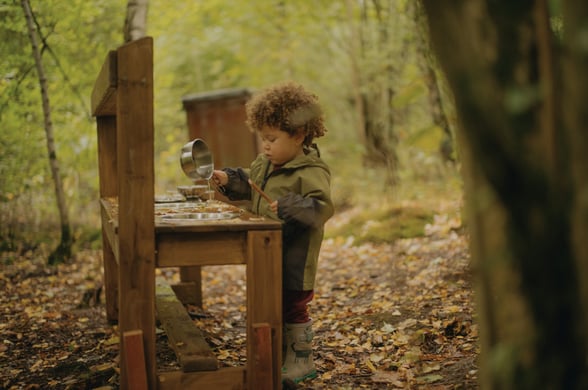 Child playing in a mud kitchen in the forest