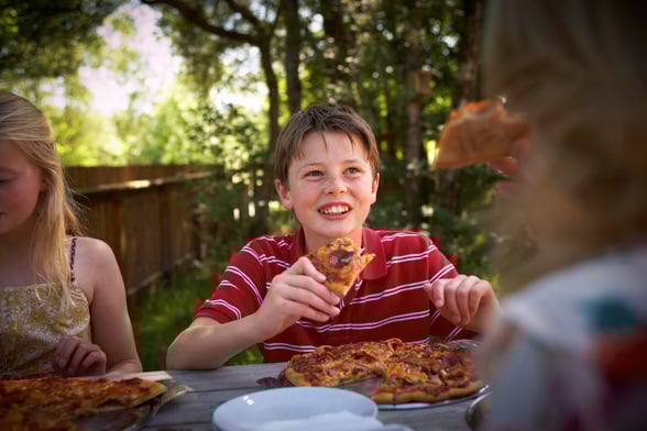 Young boy eating pizza at Forest Holidays