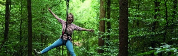 Girl swinging from the trees on a Go Ape Adventure