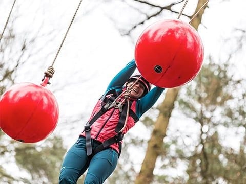 A guest swinging on suspended obstacles in the forest for the adventure challenge