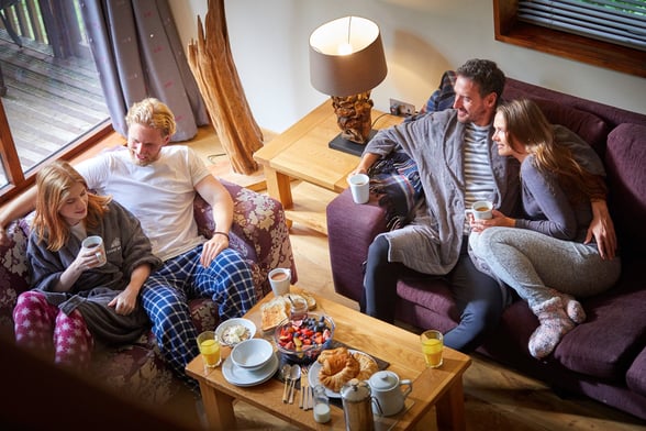 Group of friends relaxing in the log cabin lounge at Forest Holidays
