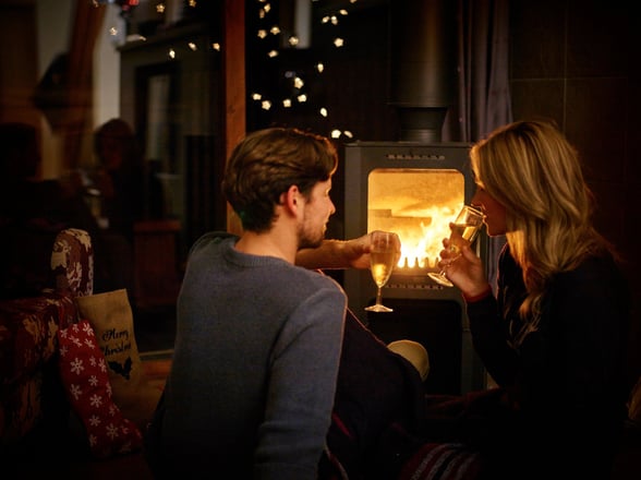 Couple celebrating next to the log burner at Forest Holidays