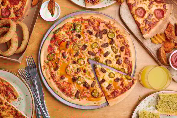 Flatlay photo of a meat feast pizza and sides