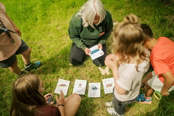 A forest ranger reading bug facts to children