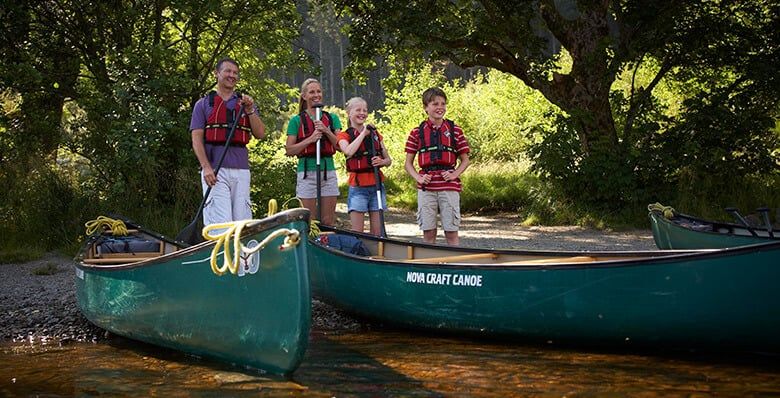Family standing next to canoes