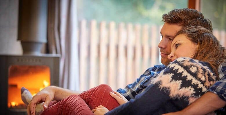 Couple enjoy time by log burning stove