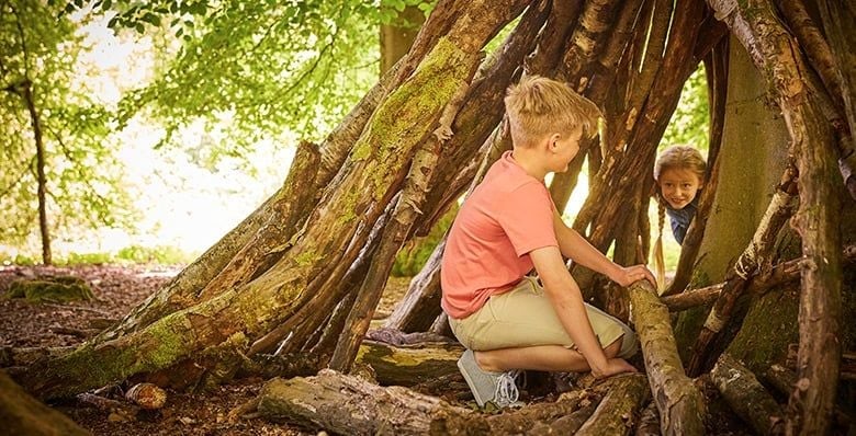 Children sat inside a forest den
