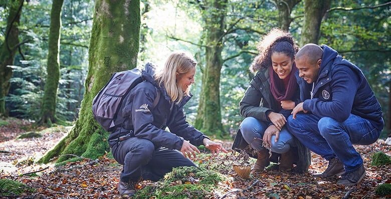 A couple on a walk in the woods with a forest ranger 