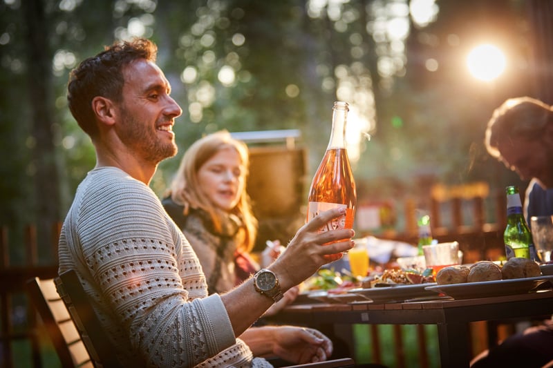 A group of friends enjoying outdoor dining in their log cabin at Thorpe Forest, Forest Holidays