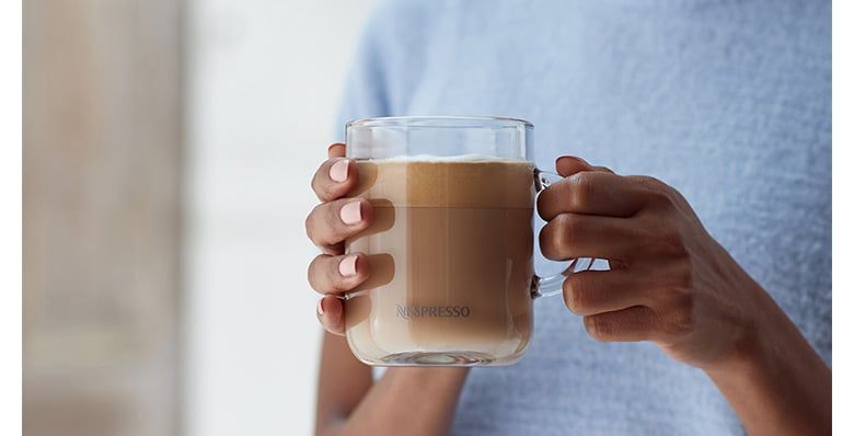 Close up of a woman holding a Nespresso coffee